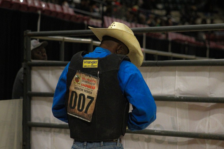 2022 Bill Pickett invitational rodeo finalist Marcus Verser wearing a cowboy hat and a wrangler vest and blue t-shirt.
