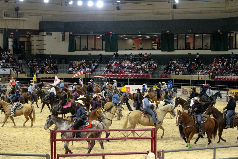 Black cowboys and cowgirls in the Bill Pickett Invitational Rodeo ride around the arena at the BPIR. 