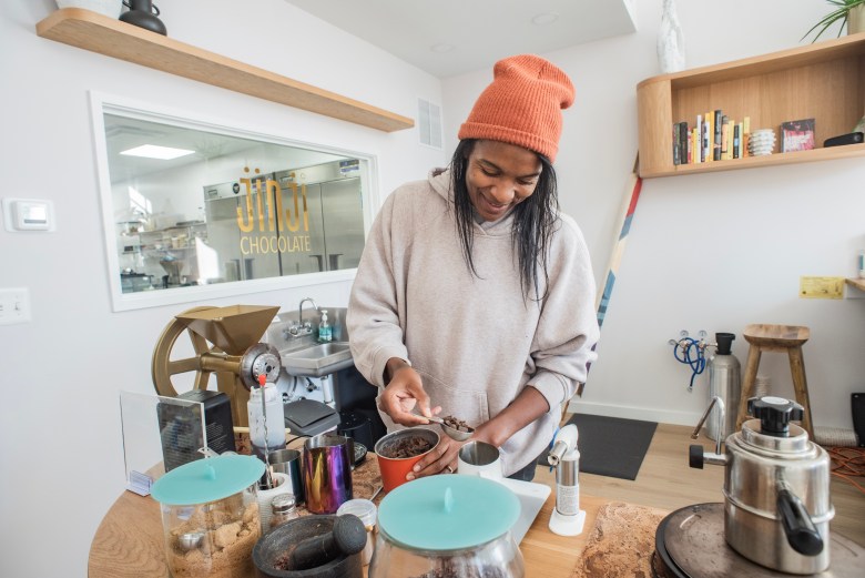 A woman with brown skin is photographed making a cup of drinking chocolate. 