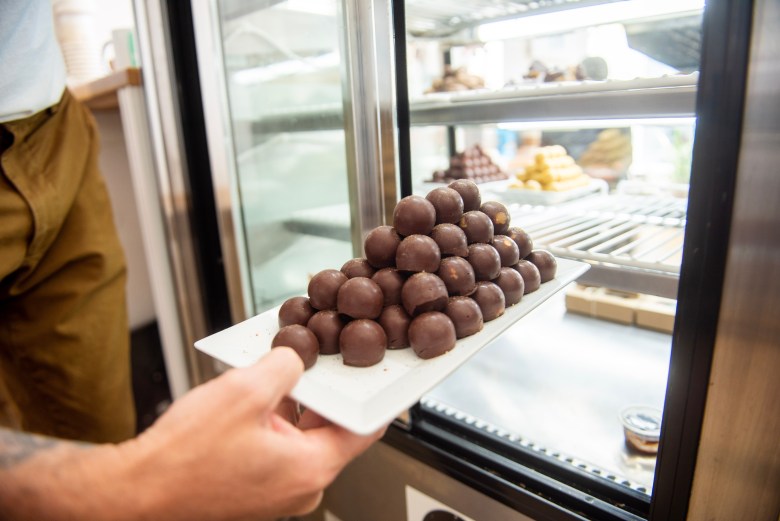 A photograph of a hand and a mound of dark choclates. 
