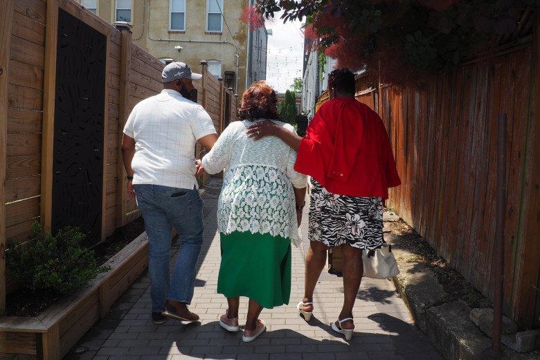 Geraldine Taylor (middle), president of The Urban Oasis, alongside friends congratulating her as they walk through the alley.