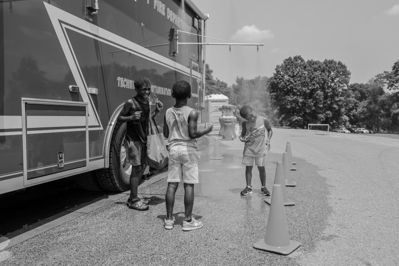 A group of young people cool off by a firetruck 