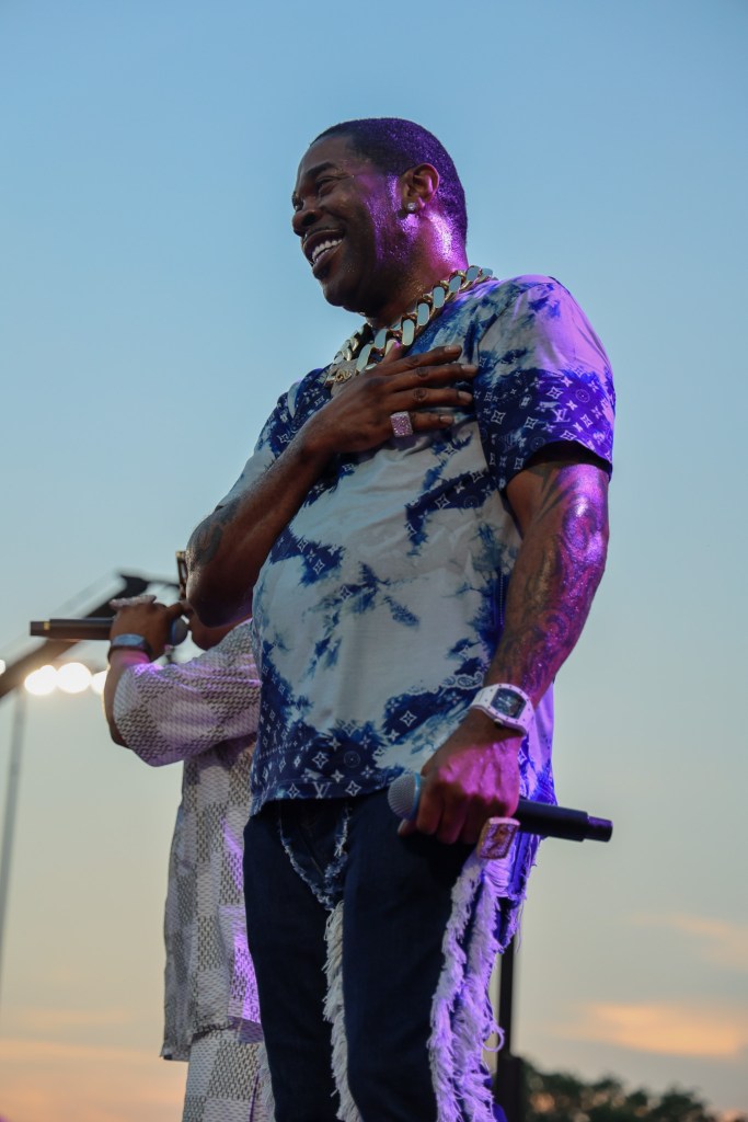 A rapper smiles with his hand on his chest 