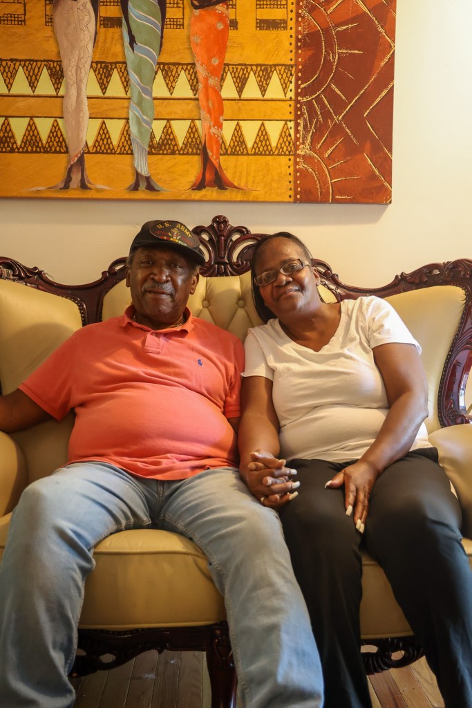a couple sits holding hands on chair. 