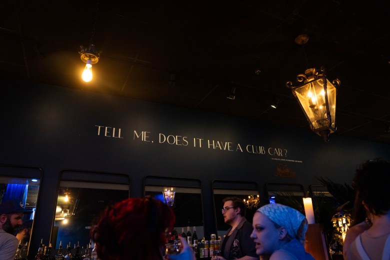 A caption above the bar reads 'TELL ME, DOES IT HAVE A CLUB CAR?' from the 1995 film "To Wong Foo, Thanks for Everything! Julie Newmar." 