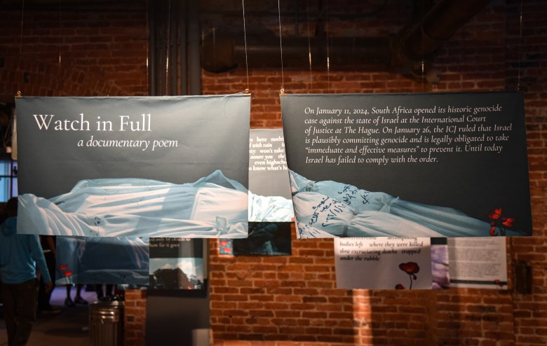 A photograph of an art installation where material is suspended from the ceiling with printed text. 
