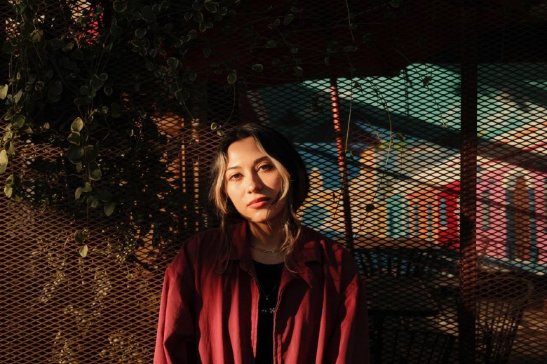 color photograph of singer eyas outside posing in a red jacket 