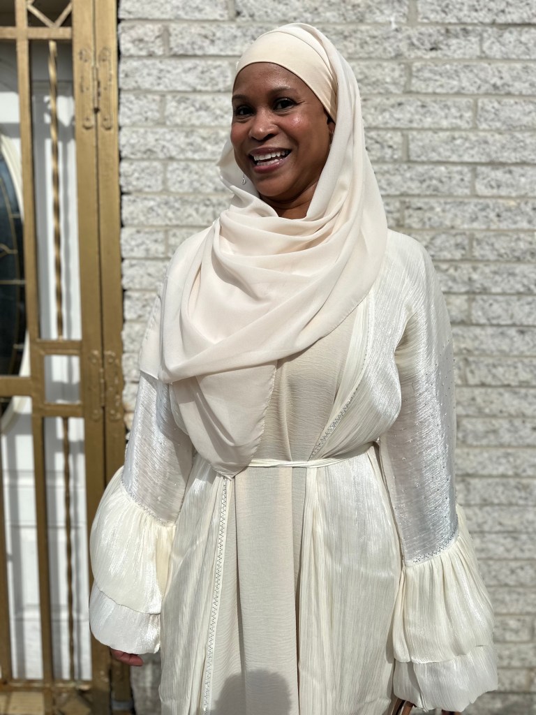 A photo of a smiling woman dressed all in white. 