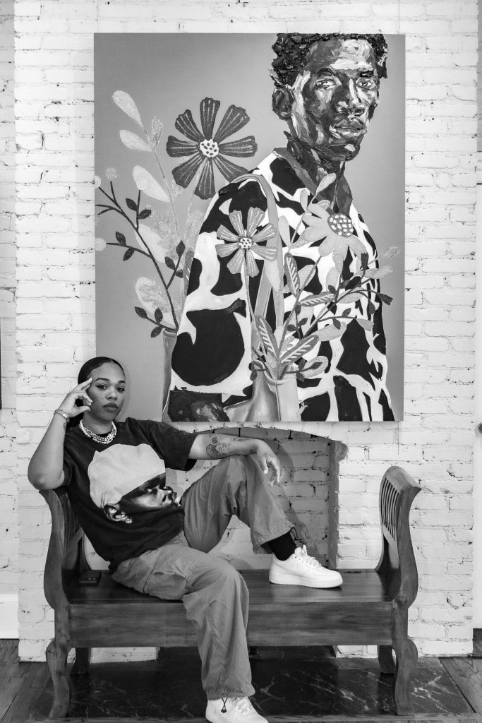 A photo of an artist posing in front of her artwork

