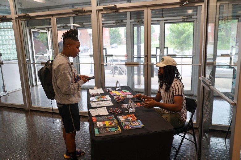 Two people are photographed talking over an information table.