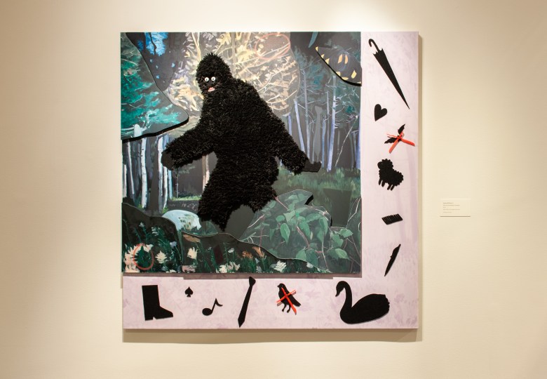 A large square artwork is shown, in the center is a large creature covered in black fur material, there are layers of leaves painted in oil paint, and a frame painted in purple, there are twelve black objects in various shapes adhered around the bottom and left hand of the artwork. The painting is on display in the Walters Art Museum. 