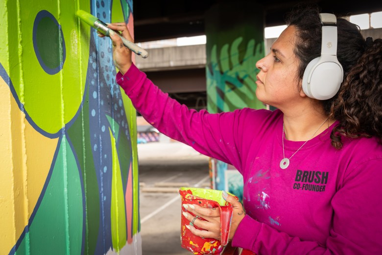 Saba Hamidi looking at a pillar in front of her as she paints it.