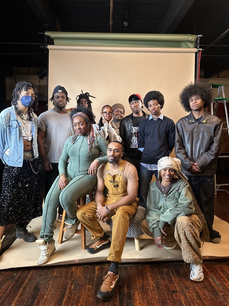 color photograph of a group of scholars and artists posing for a photo during a studio visit. 